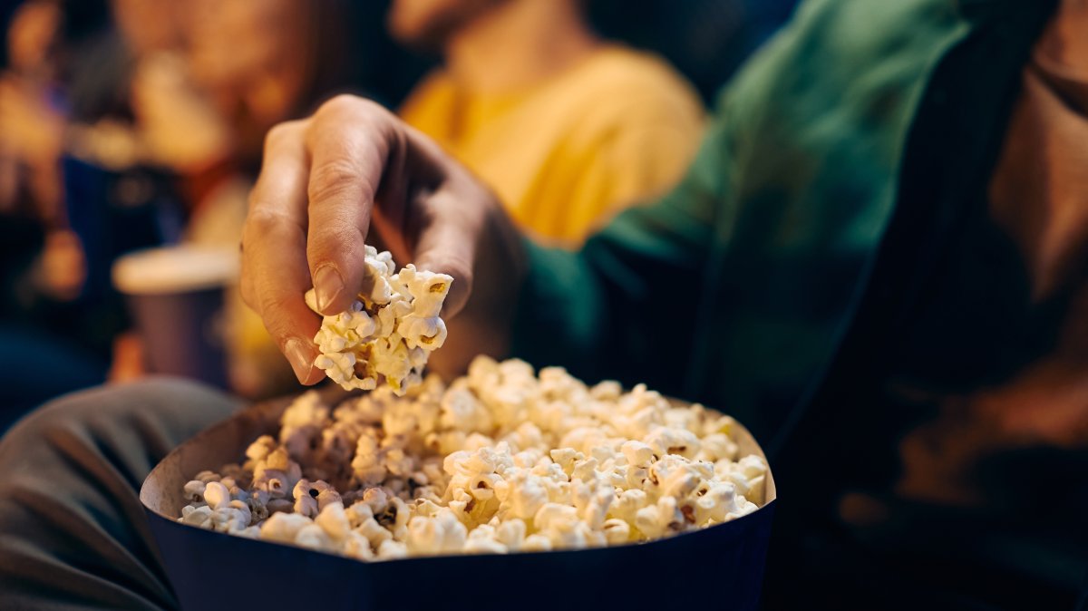 A close-up view of a man eating popcorn while watching a movie in a theater. (Shutterstock Photo)
