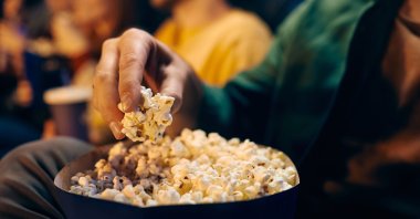 A close-up view of a man eating popcorn while watching a movie in a theater. (Shutterstock Photo)