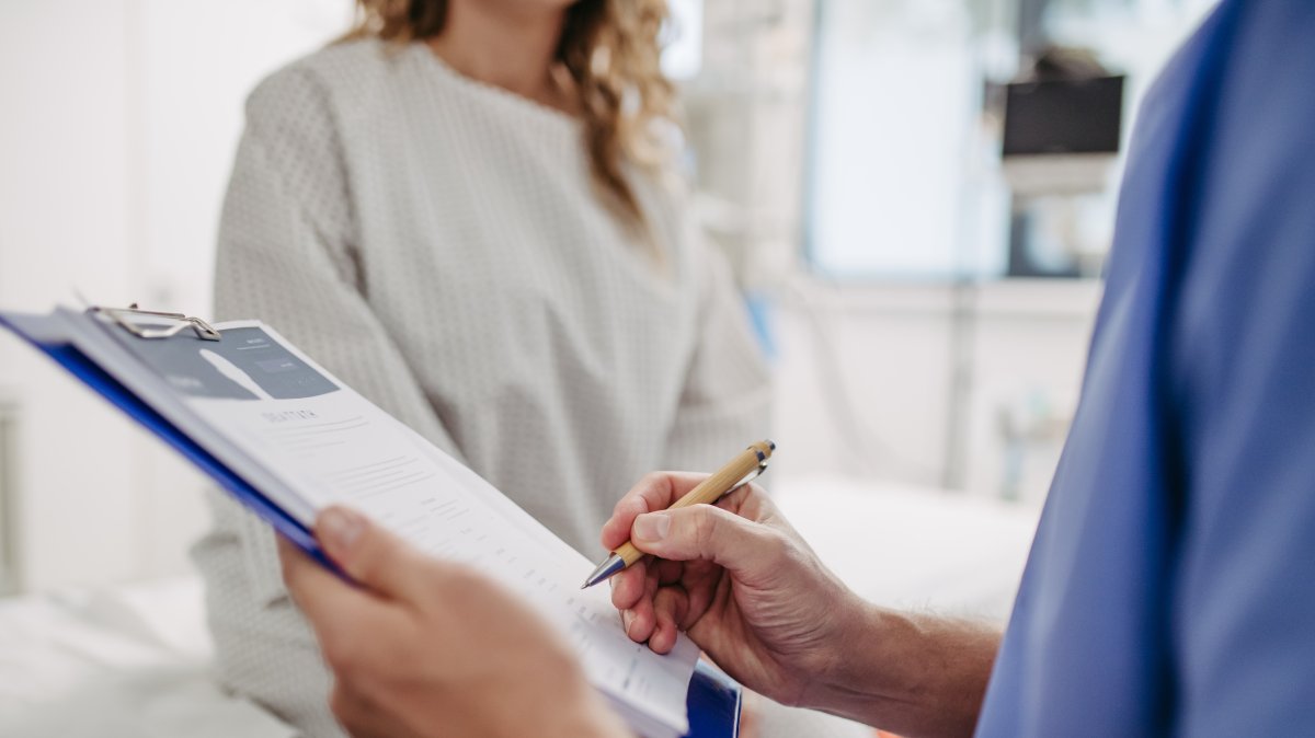 A doctor speaks with a patient while completing paperwork at a hospital. (Shutterstock Photo)