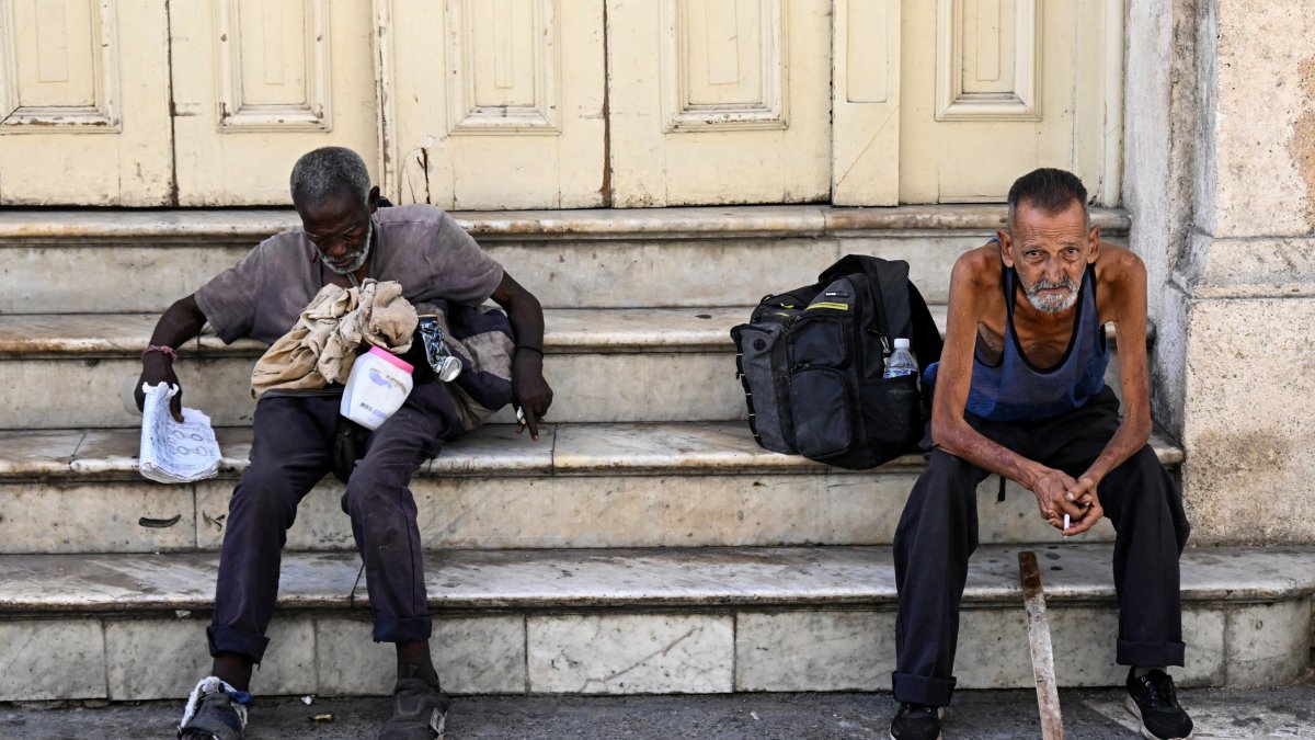 Homeless people sit on a street in Havana, July 21, 2025. (AFP File Photo)