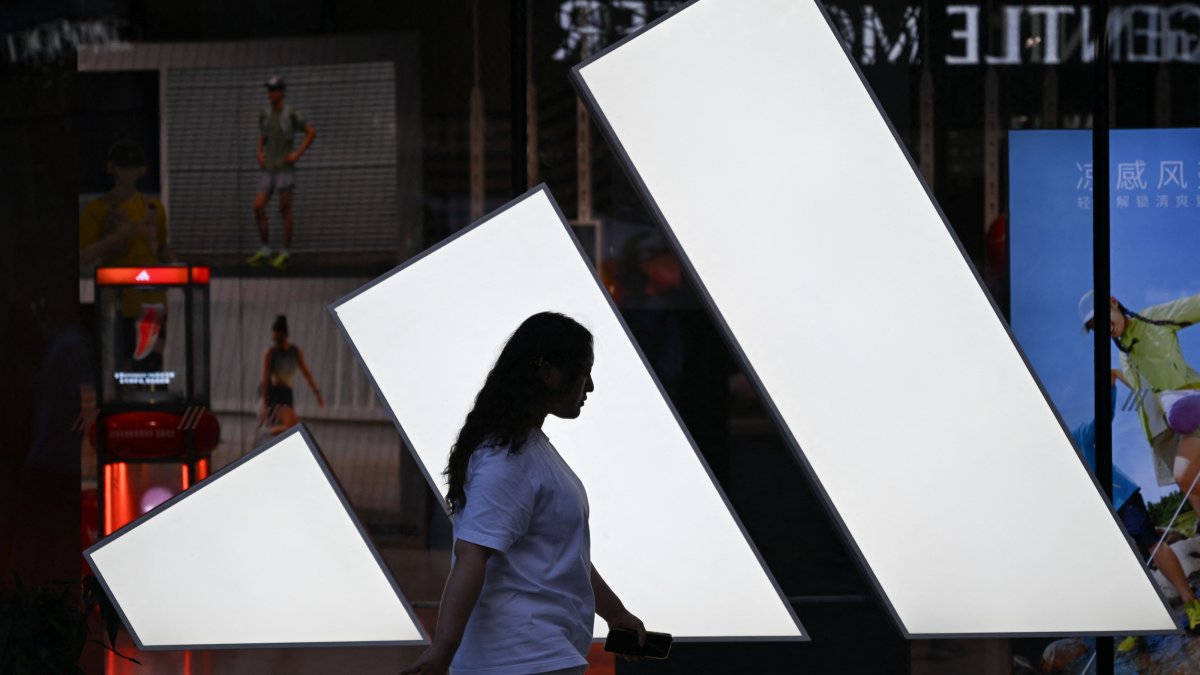 A woman walks past an Adidas store at a mall in Beijing, China, Aug. 16, 2026. (AFP Photo)