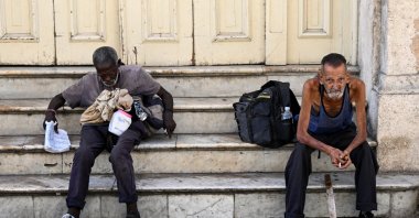 Homeless people sit on a street in Havana, July 21, 2025. (AFP File Photo)