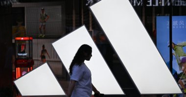 A woman walks past an Adidas store at a mall in Beijing, China, Aug. 16, 2026. (AFP Photo)