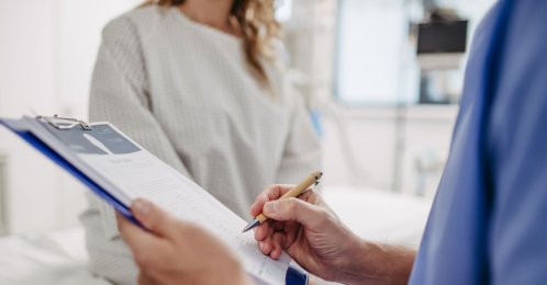 A doctor speaks with a patient while completing paperwork at a hospital. (Shutterstock Photo)
