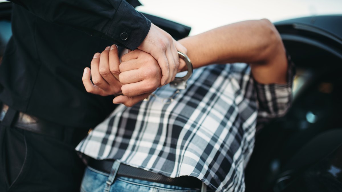 A police officer arrests a suspect on the road. (Shutterstock Photo)