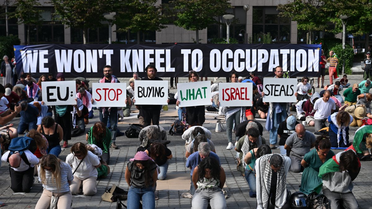 Flotilla for Gaza activists hold placards reading "EU: stop buying what Isreal steals" among protesters and in front of a banner that reads: “We won't kneel to occupation”, during a demonstration to demand EU leaders to ban goods from illegal Israeli settlements, in Brussels on June 17, 2026. (AFP File Photo)