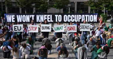 Flotilla for Gaza activists hold placards reading "EU: stop buying what Isreal steals" among protesters and in front of a banner that reads: “We won't kneel to occupation”, during a demonstration to demand EU leaders to ban goods from illegal Israeli settlements, in Brussels on June 17, 2026. (AFP File Photo)