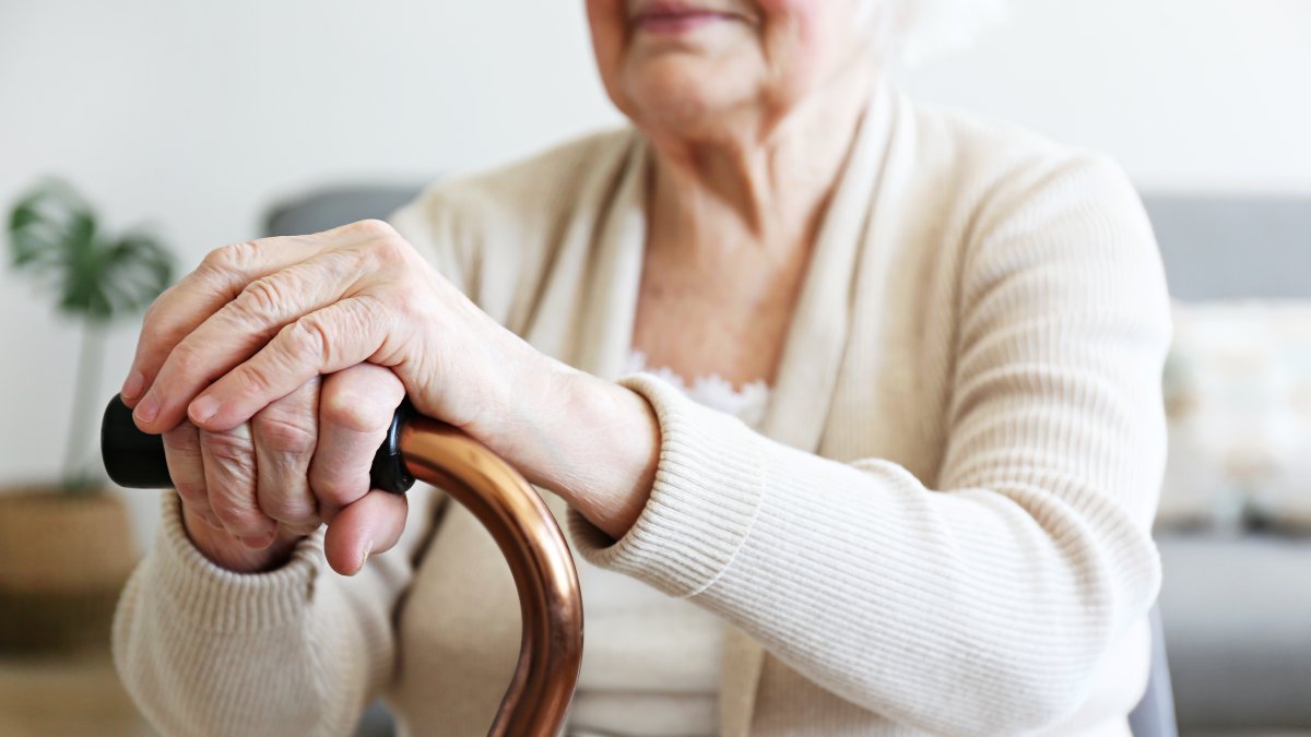 An elderly woman holds a walking cane in a nursing home. (Shutterstock Photo)