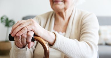 An elderly woman holds a walking cane in a nursing home. (Shutterstock Photo)
