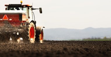 Tractor spreading artificial fertilizers in a field. (Shutterstock Photo)