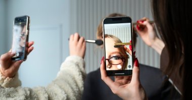 A woman has her makeup done while being photographed. (Shutterstock Photo)