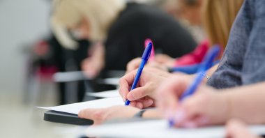 A student writes on a test paper during an exam. (Shutterstock Photo)