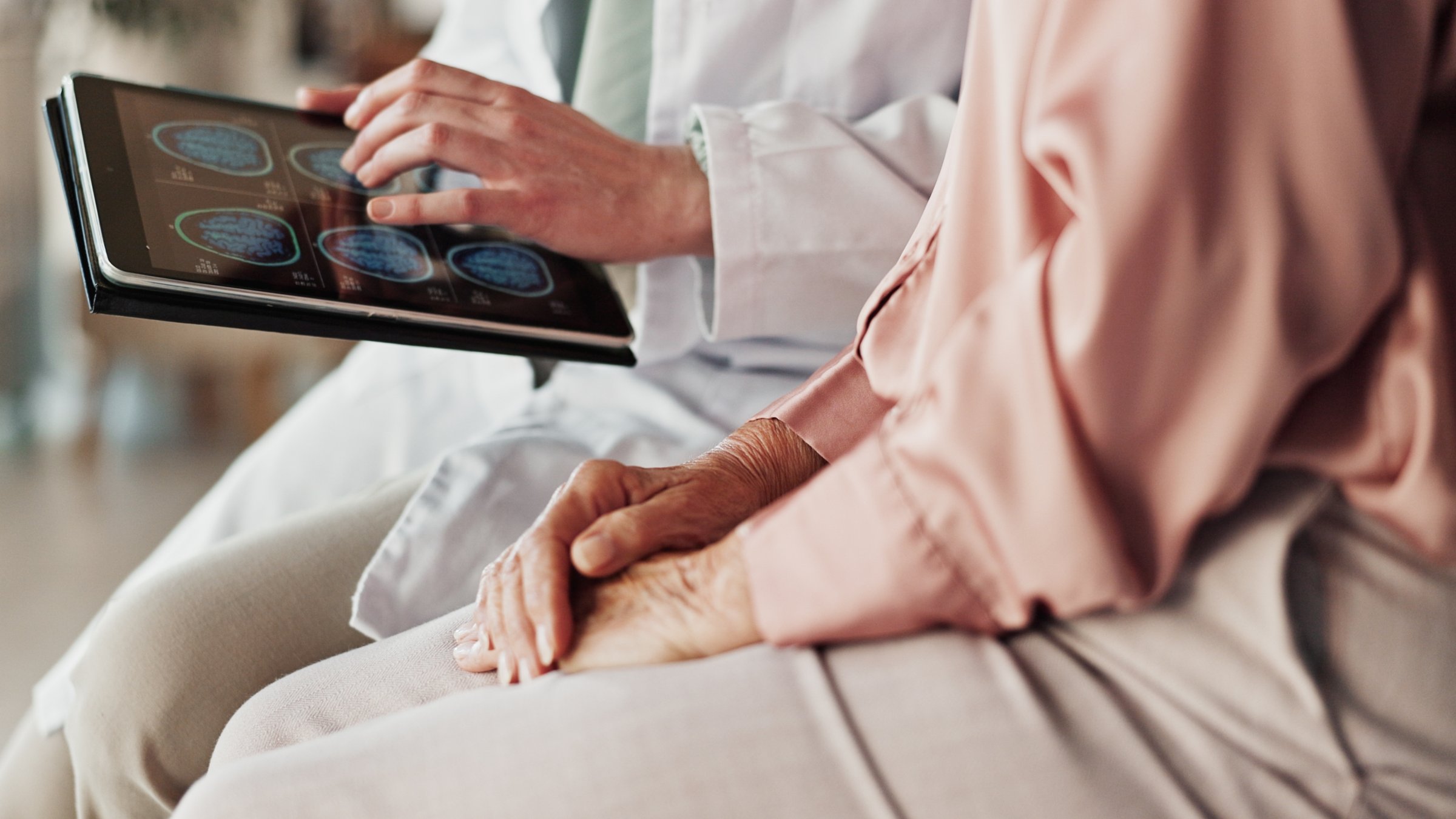 Hands of a patient and a doctor holding a tablet. (Shutterstock Photo)