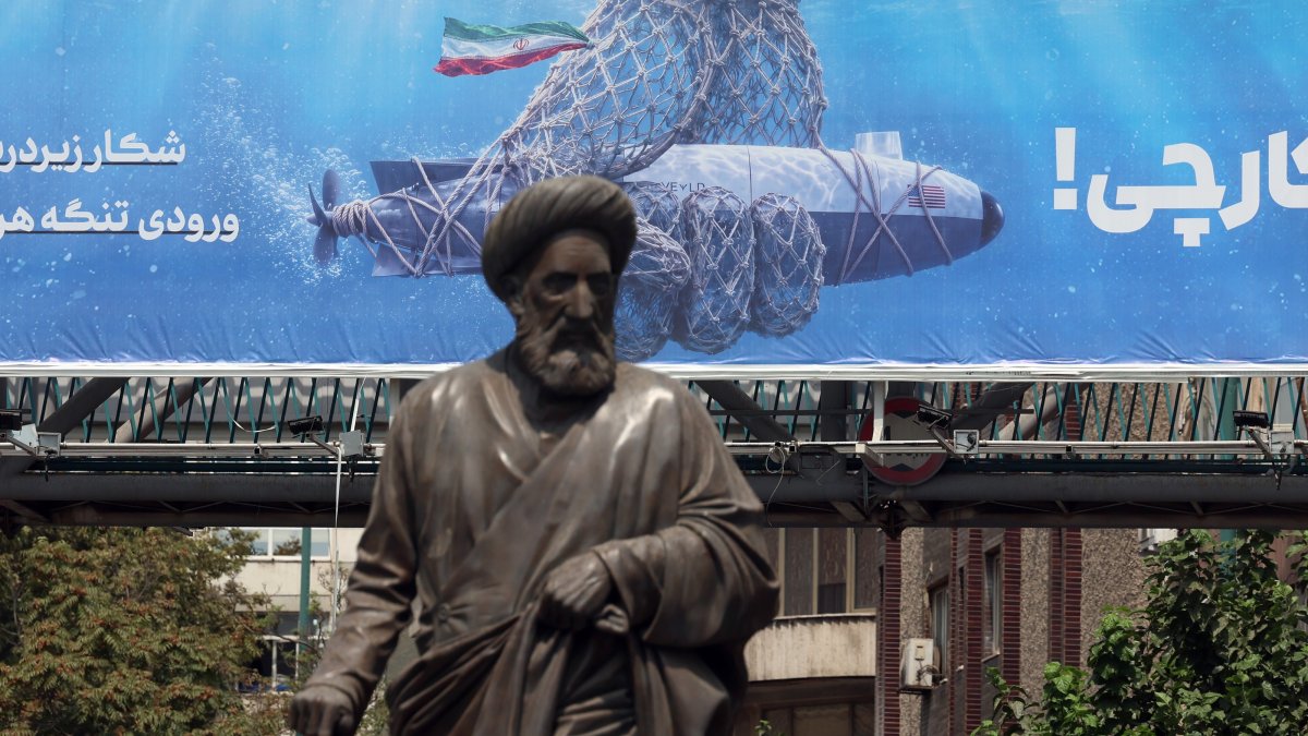 A statue stands in front of a billboard hanging on a pedestrian bridge featuring a U.S. underwater drone captured by the Iranian military and a sentence reading in Persian, ‘Hunting the Hunter,' in Tehran, Iran, Sept. 9, 2026. (EPA Photo)