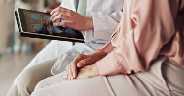 Hands of a patient and a doctor holding a tablet. (Shutterstock Photo)