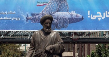 A statue stands in front of a billboard hanging on a pedestrian bridge featuring a U.S. underwater drone captured by the Iranian military and a sentence reading in Persian, ‘Hunting the Hunter,' in Tehran, Iran, Sept. 9, 2026. (EPA Photo)