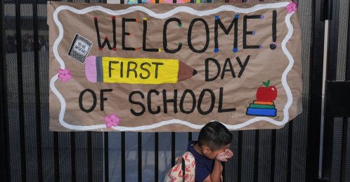 A student wipes his face while his mother takes a photo of him with a sign on the first day of school at Betsy Ross Elementary School, California, U.S., Aug. 6, 2026. (AP Photo)
