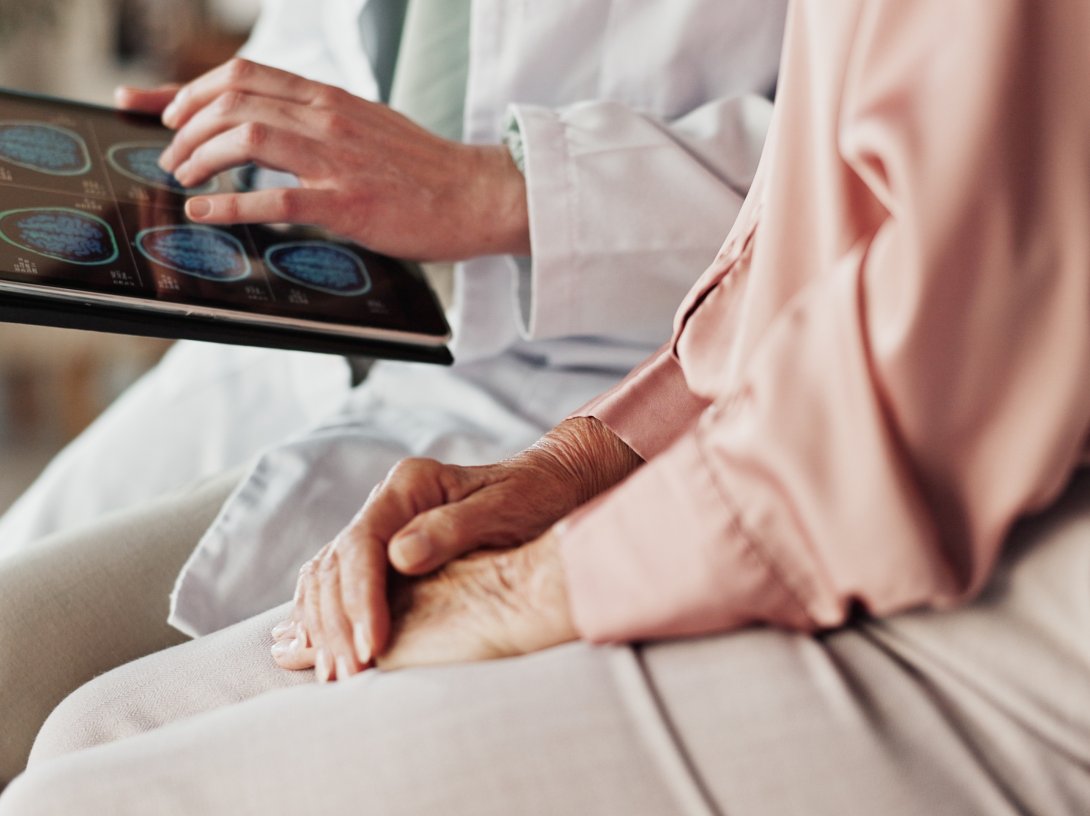 Hands of a patient and a doctor holding a tablet. (Shutterstock Photo)