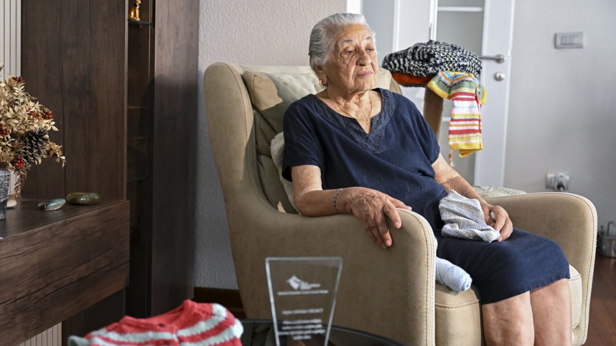 Sabahat Ekerci sits next to the sweaters and other knitwear she made for children in need, Istanbul, Türkiye, Aug. 21, 2026. (AA Photo) 