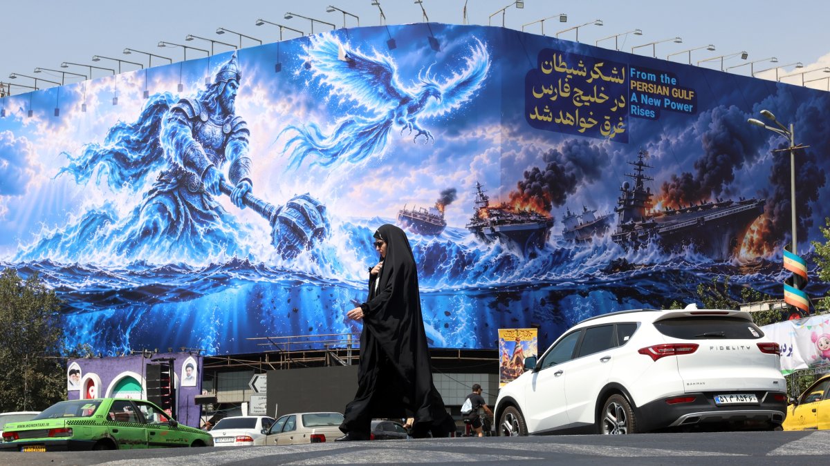 A woman walks next to an anti-U.S. billboard reading in Persian 'The devil army will be drown in the Persian Gulf' at the Enqelab square in Tehran, Iran, Sept. 14, 2026. (EPA Photo)