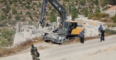 Israeli forces stand guard near heavy machinery during the demolition of a Palestinian building near Hebron in the Israeli-occupied West Bank, Palestine, Sept. 10, 2026. (Reuters Photo)