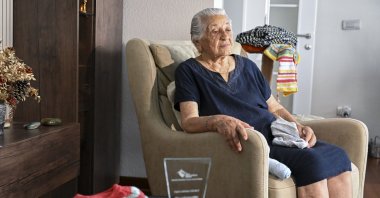 Sabahat Ekerci sits next to the sweaters and other knitwear she made for children in need, Istanbul, Türkiye, Aug. 21, 2026. (AA Photo) 