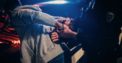 Police officers detain a suspect during an operation targeting criminal organizations. (Shutterstcok Photo)