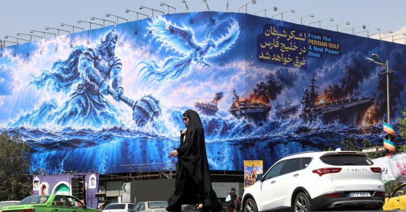 A woman walks next to an anti-U.S. billboard reading in Persian 'The devil army will be drown in the Persian Gulf' at the Enqelab square in Tehran, Iran, Sept. 14, 2026. (EPA Photo)