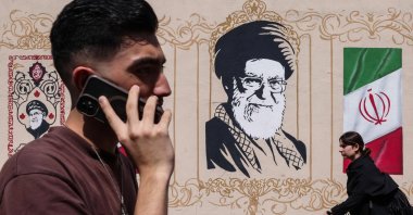 People walk past a wall decorated with the image of the assassinated Iranian supreme leader Ayatollah Ali Khamenei and the national flag, Tehran, Iran, Sept. 14, 2026. (AFP Photo)
