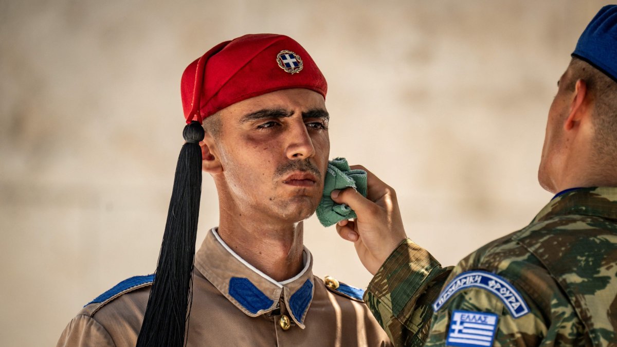 A soldier wipes the sweat from the face of a Greek Presidential Guard (Evzonas) as he stands guard at the Tomb of the Unknown Soldier, Athens, Greece, July 21, 2026. (AFP Photo)