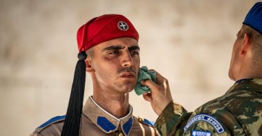 A soldier wipes the sweat from the face of a Greek Presidential Guard (Evzonas) as he stands guard at the Tomb of the Unknown Soldier, Athens, Greece, July 21, 2026. (AFP Photo)