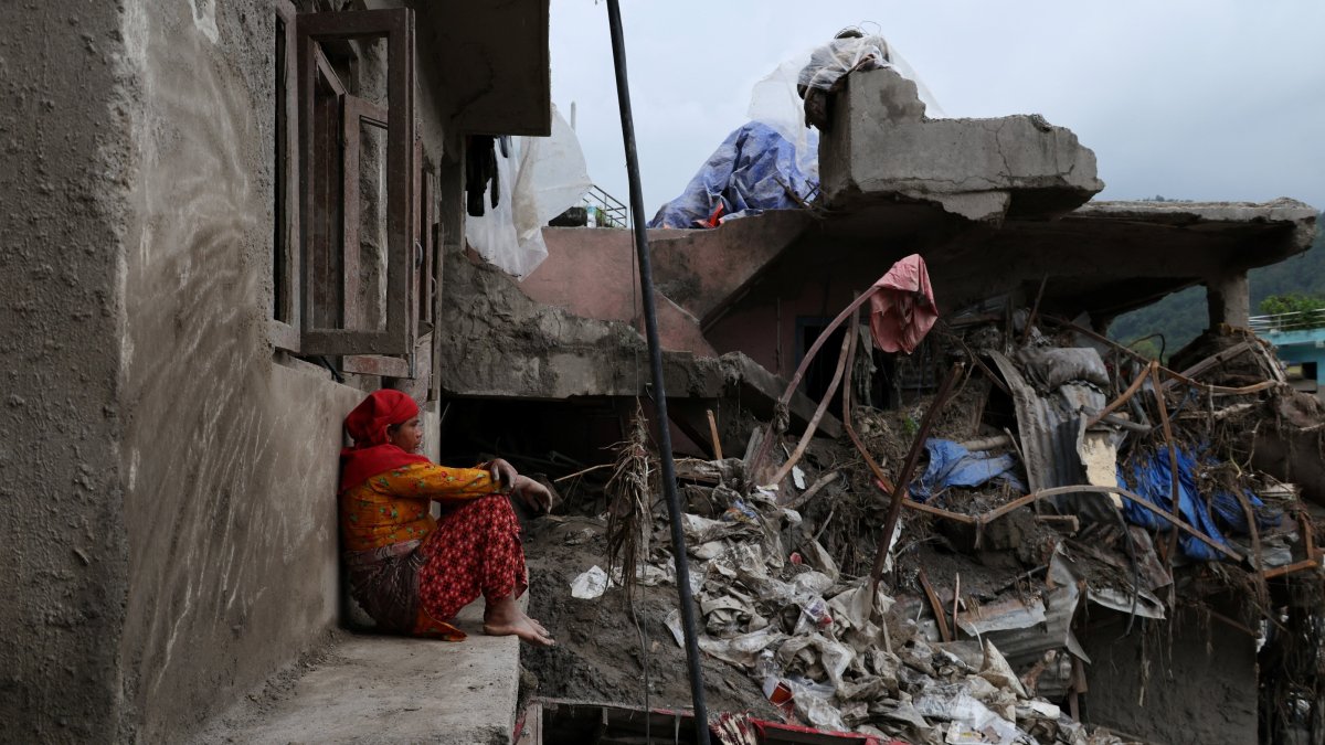 A local day laborer rests outside a flood-damaged house after hanging laundry for an employer in the aftermath of flash floods and mudslides in Devighat, Nuwakot district, Nepal, Sept. 7, 2026. (Reuters Photo)