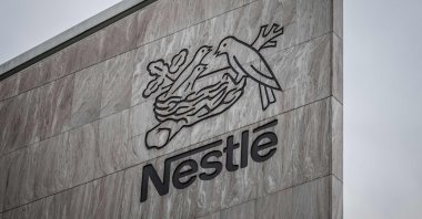 This photograph shows a bird of the crow family flying next to the logo of Swiss food giant Nestle on the facade of its headquarters in Vevey, western Switzerland, Oct. 14, 2025. (AFP Photo)