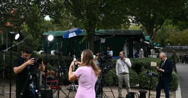 Members of the media on Pebble Beach, where television networks broadcast from the North Lawn of the White House, in Washington, DC, Sept. 18, 2026. (AFP Photo)