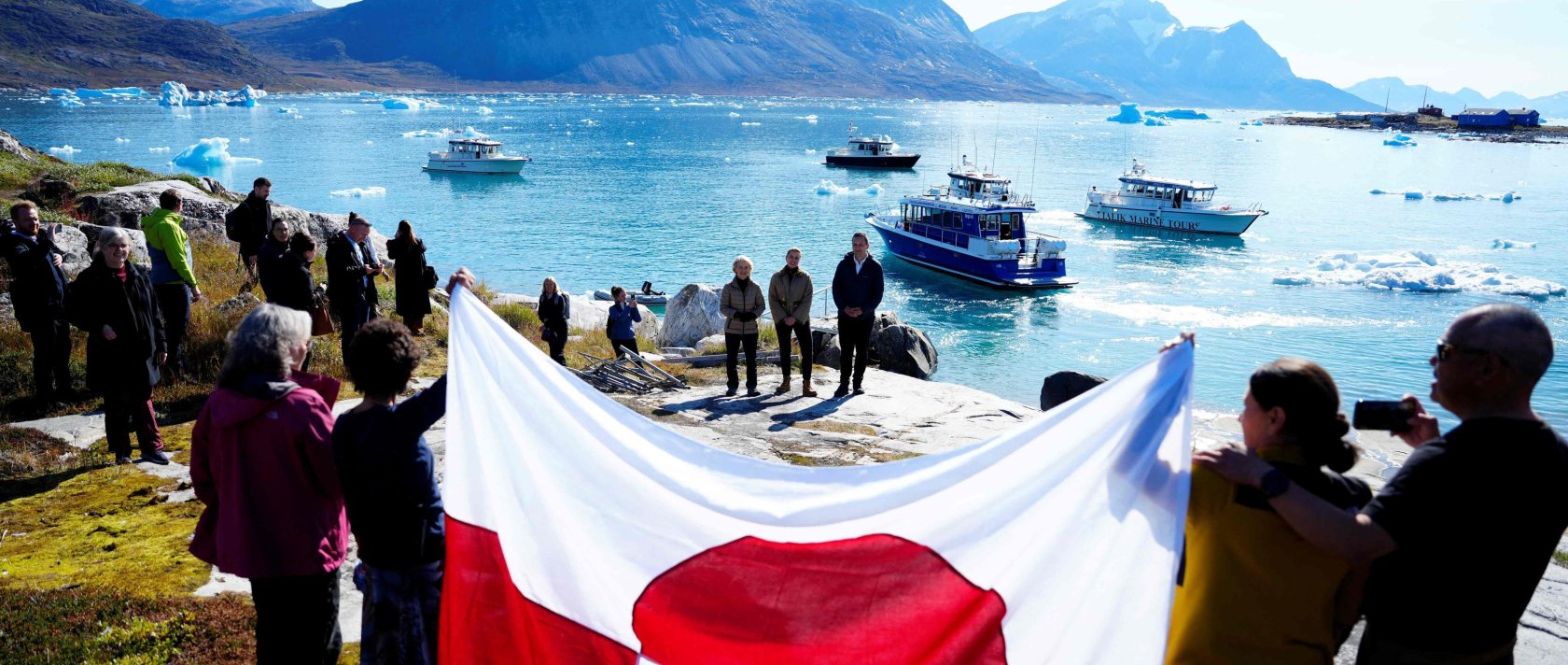 Bystanders display a flag of Greenland as European Commission President Ursula von der Leyen (back L), Greenland's Prime Minister Jens-Frederik Nielsen (back R) and Denmark's Prime Minister Mette Frederiksen visit Qoornoq, Greenland, Sept. 6, 2026. (AFP Photo)