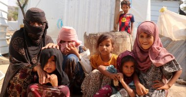 Rawya Hassan, a mother of seven, sits with her children outside their hut at the al-Bireen camp for displaced people who fled fighting between the Houthis and forces of Yemen's internationally recognized government, Taiz province, Yemen, Sept. 17, 2026. (Reuters Photo)