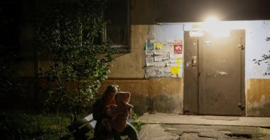 A woman with her daughter sits at the site of an apartment building hit by a Russian drone strike, amid Russia's attack on Ukraine, Kyiv, Ukraine, Sept. 11, 2026. (Reuters Photo)
