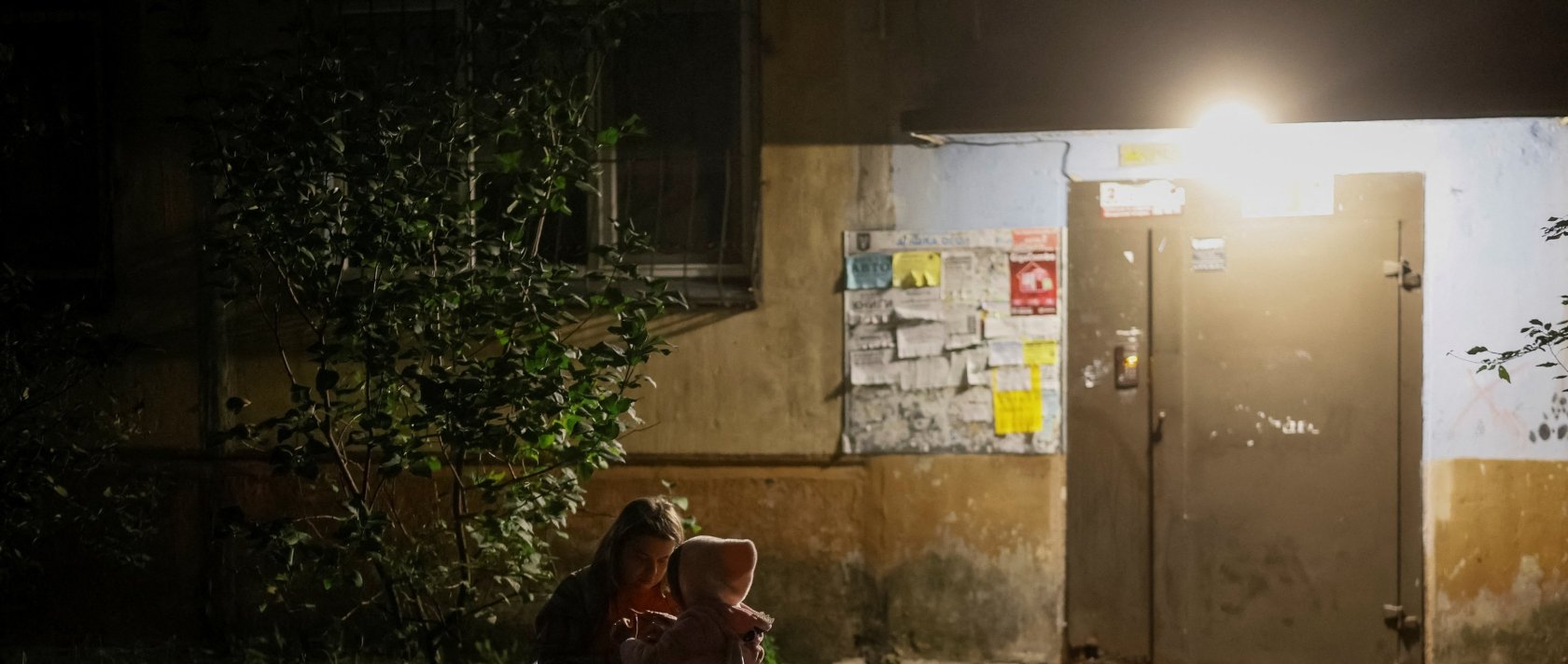 A woman with her daughter sits at the site of an apartment building hit by a Russian drone strike, amid Russia's attack on Ukraine, Kyiv, Ukraine, Sept. 11, 2026. (Reuters Photo)