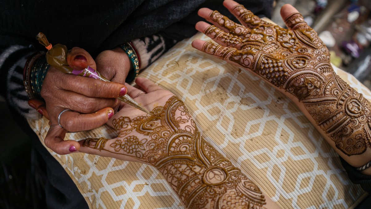 An Indian artist applies henna to the hand of a girl ahead of the Eid Al-Fitr festival, Srinagar, Jammu and Kashmir, March 18, 2026. (Getty Images Photo)
