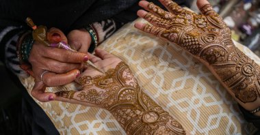 An Indian artist applies henna to the hand of a girl ahead of the Eid Al-Fitr festival, Srinagar, Jammu and Kashmir, March 18, 2026. (Getty Images Photo)