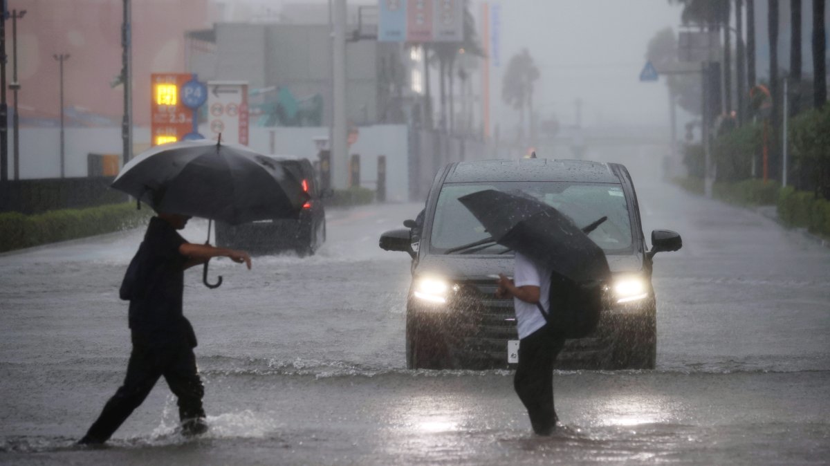 People cross a flooded street in Funabashi, Chiba Prefecture, near Tokyo, Japan, Sept. 21, 2026. (EPA Photo)