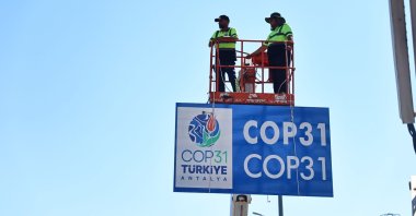 Municipal workers install billboards ahead of the COP31 summit, southern Antalya province, Türkiye, Aug. 25, 2026. (IHA Photo)