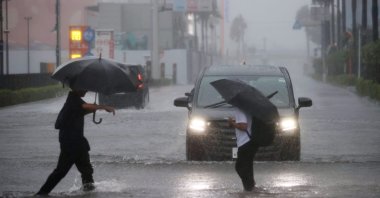 People cross a flooded street in Funabashi, Chiba Prefecture, near Tokyo, Japan, Sept. 21, 2026. (EPA Photo)