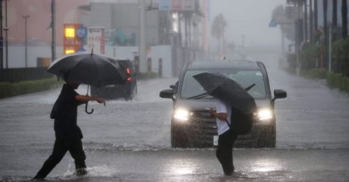 People cross a flooded street in Funabashi, Chiba Prefecture, near Tokyo, Japan, Sept. 21, 2026. (EPA Photo)