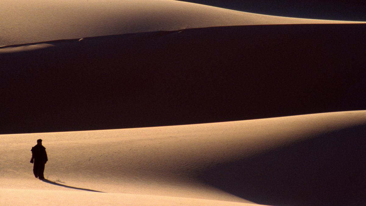 A view of a solitary figure in the dunes of the Fezzan Desert, Libya, March 19, 2002. (Getty Images Photo)