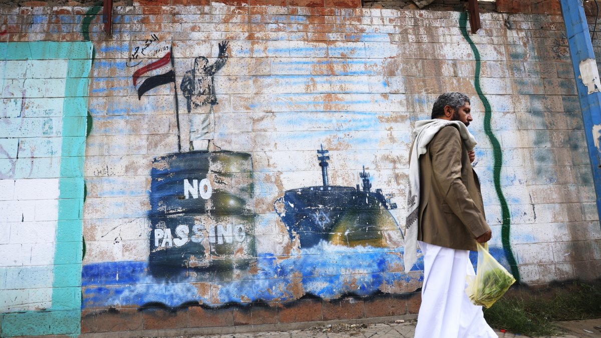 A person walks past the shuttered Saudi embassy with a graffitied wall depicting a Houthi fighter stopping a ship off the coast of Yemen, in Sana'a, Yemen, Sept. 11, 2026. (EPA Photo)