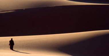 A view of a solitary figure in the dunes of the Fezzan Desert, Libya, March 19, 2002. (Getty Images Photo)