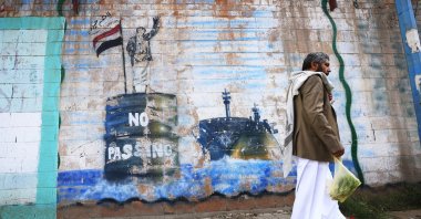 A person walks past the shuttered Saudi embassy with a graffitied wall depicting a Houthi fighter stopping a ship off the coast of Yemen, in Sana'a, Yemen, Sept. 11, 2026. (EPA Photo)