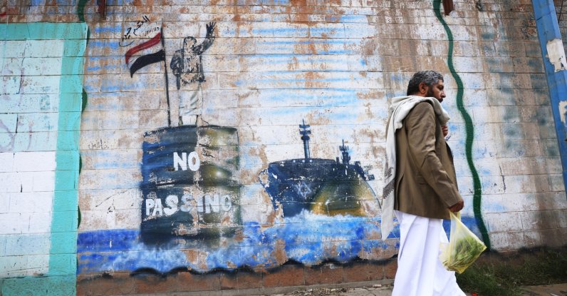 A person walks past the shuttered Saudi embassy with a graffitied wall depicting a Houthi fighter stopping a ship off the coast of Yemen, in Sana'a, Yemen, Sept. 11, 2026. (EPA Photo)