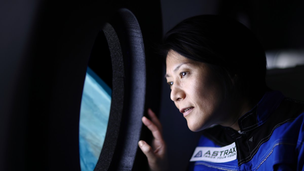 A commercial space traveler looking at the Earth through the window of a spaceship. (Getty Images Photo)